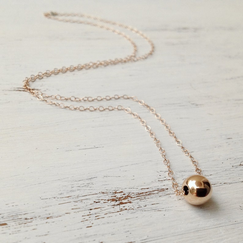 Puede incluir: Un collar de cadena de oro con un solo colgante de cuentas redondas de oro grande.