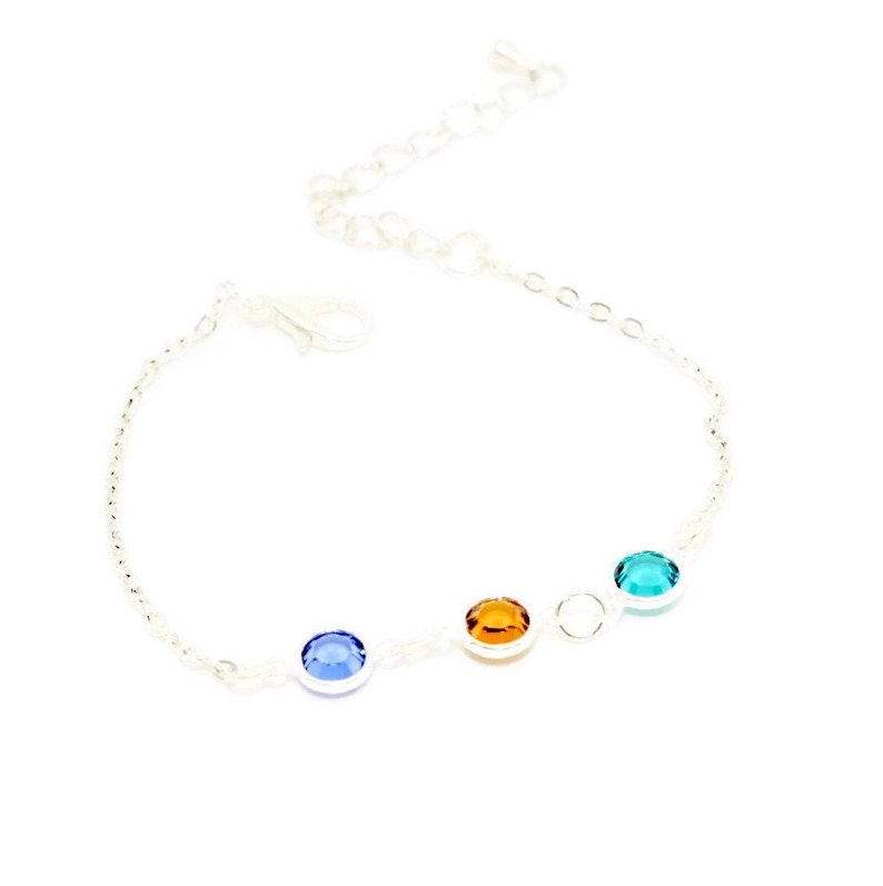 May include: A silver chain bracelet with four round gemstones. The gemstones are blue, orange, and green.