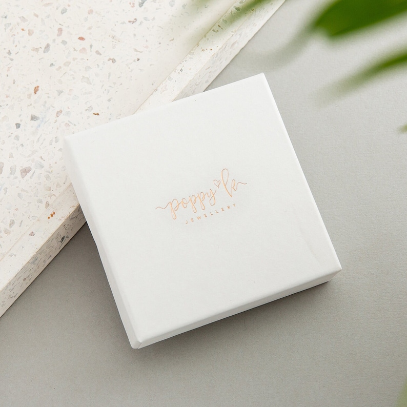 May include: White square box with the text "poppy & co. jewellery" in gold lettering.