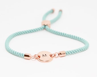 May include: A light blue adjustable bracelet with a rose gold charm featuring the letter "M".