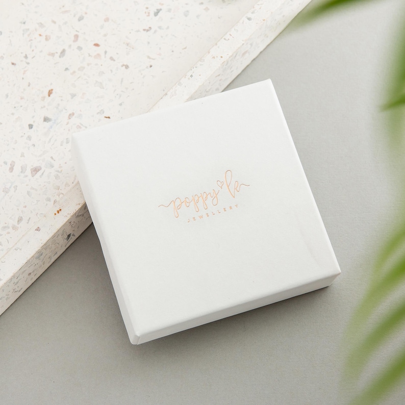 May include: White square box with the text "poppy & co. jewellery" in gold lettering.