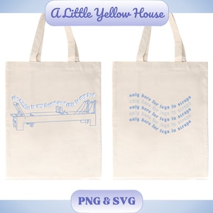 May include: Two white tote bags with blue text and illustrations. The left bag has a blue illustration of a pilates reformer with the text "the studio is my home and this is my bed". The right bag has the text "only here for legs in straps" repeated in a curved pattern.