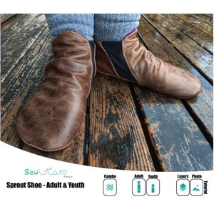 May include: A pair of brown leather moccasin-style shoes with black fabric accents. The shoes are on a wooden surface. The text "Sprout Shoe - Adult & Youth" is visible below the shoes.