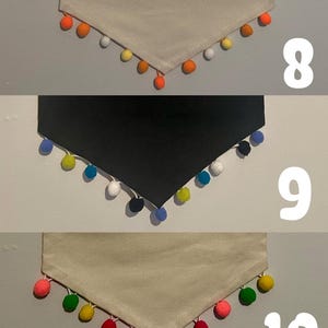 May include: Three fabric bandanas with different colored pom-poms around the edges. The first bandana is white with orange pom-poms, the second is black with blue pom-poms, and the third is beige with green, yellow, red, and pink pom-poms.