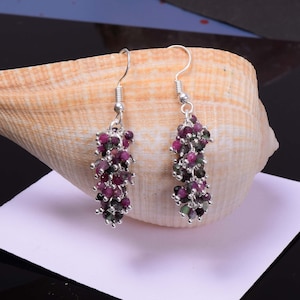 Könnte beinhalten: Ein Paar silberne Ohrhänger mit einem Cluster aus rosa und grünen Edelsteinen. Die Ohrringe sind etwa 5 cm lang.