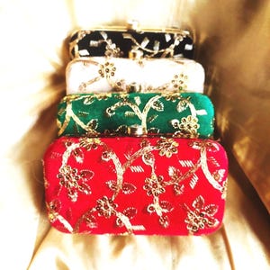 Puede incluir: Cuatro bolsos de mano rectangulares apilados. Los bolsos son negros, blancos, verdes y rojos. Cada bolso está decorado con bordados florales dorados. Los bolsos tienen un cierre dorado.
