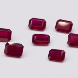 Puede incluir: Siete rubíes rojos de corte rectangular sobre un fondo blanco.