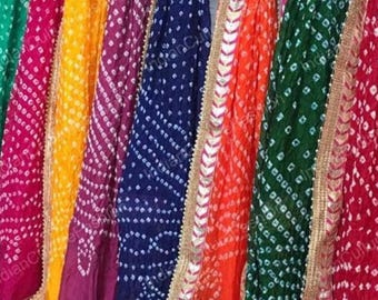 May include: A collection of colorful, patterned fabrics in shades of green, pink, yellow, purple, blue, orange, and red. Each fabric has a white dotted design and a gold-colored trim. The fabrics are likely textiles or scarves.