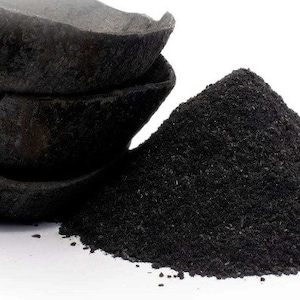 Peut inclure: Gros plan sur des morceaux de charbon de bois noir et une pile de poudre noire fine. Le charbon de bois a une surface rugueuse et texturée. La poudre est d'un noir mat foncé, contrastant avec le fond blanc. Produit naturel.