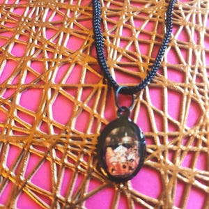 May include: A black chain necklace with a round pendant featuring a colorful image of a floral arrangement.
