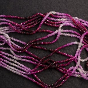 Può includere: Un filo di perle di rubino in varie tonalità di rosa e rosso. Le perle sono sfaccettate e hanno una forma quadrata. Le perle sono infilate su un filo trasparente.