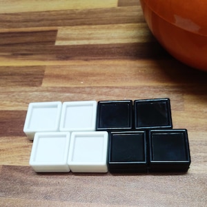 May include: A set of black and white square tiles. The tiles are arranged in a pattern, with the black tiles on top of the white tiles.