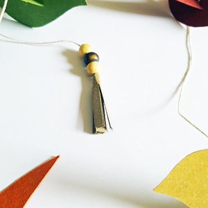 Guirlande d’oiseaux colorés en papier recyclé faits main, suspendus sur un fil blanc.