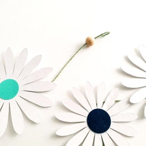 Guirlande florale en papier accrochée à un mur blanc