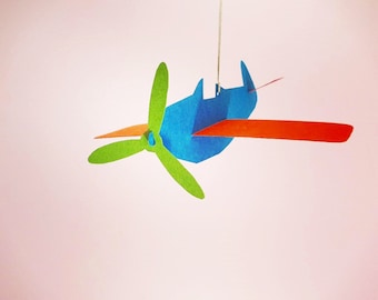 May include: A blue, orange, and green paper airplane mobile hanging from a white ceiling.