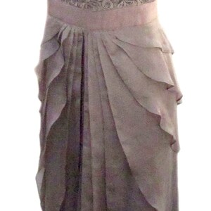 May include: A mauve lace and chiffon dress with a ruffled skirt. The dress has a fitted bodice and short sleeves.