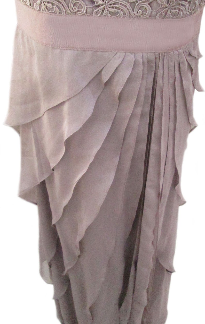 May include: A mauve-colored dress with a layered ruffle skirt. The skirt is made of a soft, flowing fabric and has a delicate, feminine look.