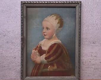 May include: A framed portrait painting of a young child wearing a white bonnet and a red and gold striped garment. The child is holding a small, light-coloured object in their hands. The painting is enclosed in a textured, silver-toned frame.