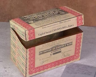 May include: A rectangular decorative box featuring a vintage financial document design with cream, black, and red accents. The lid and sides display text including "Société des Mines de Kilo-Moto," "Bruxelles," and "Capital Social 230.000.000 de Francs."
