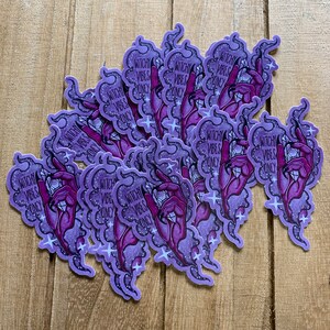 May include: A stack of purple and pink stickers with a hand holding a crystal and the text "Witchy Vibes Only" on each sticker.