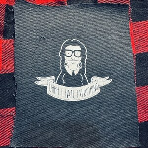 May include: Black and white iron-on patch featuring a cartoon character with glasses and the text "Uhhh I hate everything".
