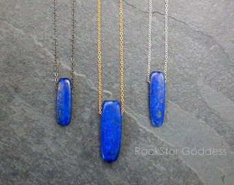 May include: Three necklaces with different chain styles, each featuring a rectangular lapis lazuli pendant. The pendants are a deep blue color with gold flecks.