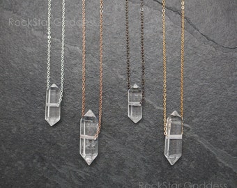 May include: Five necklaces with clear crystal pendants hanging from silver, rose gold, black, and gold chains against a dark gray background. The text "RockStar Goddess" appears at the bottom of the image.