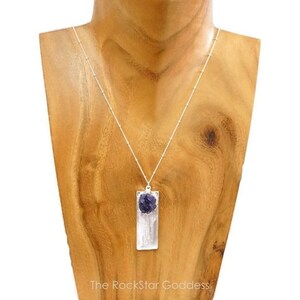 May include: A silver chain necklace with a rectangular pendant featuring a clear selenite crystal and a purple amethyst stone.