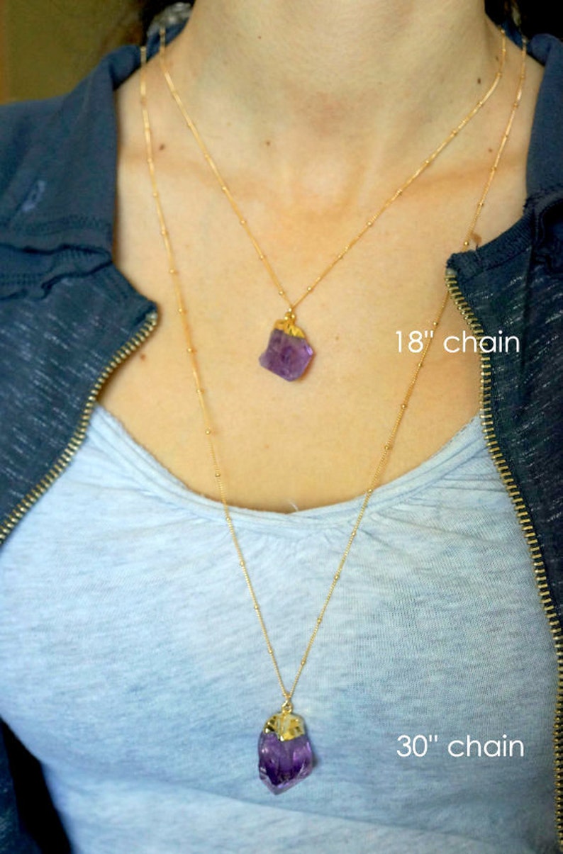 May include: Two gold chains with amethyst crystal pendants. The shorter chain is 18 inches long and the longer chain is 30 inches long.