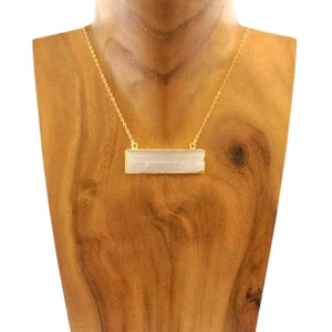 Pode incluir: Um colar de corrente de ouro com um pingente retangular de cristal de selenite. O pingente &eacute; de um branco claro transl&uacute;cido com um padr&atilde;o estriado.