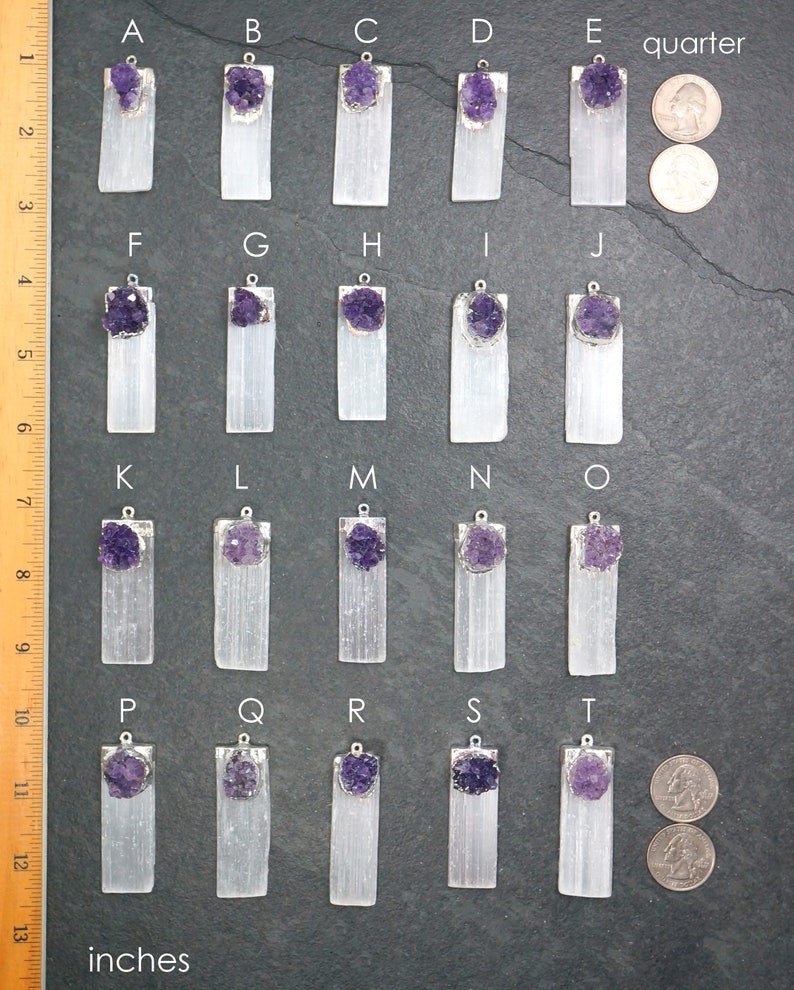 May include: Twenty selenite crystal pendants with amethyst clusters, arranged in rows labeled A through T. Each pendant is approximately 1.5 inches long and features a silver bail. A U.S. quarter is included for scale.