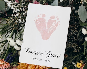 Peut inclure: Une carte blanche avec une empreinte de pied en forme de cœur rose. Le texte "Emerson Grace" et "June 26, 2021" est imprimé sous l'empreinte.