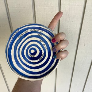 Op de afbeelding: Een wit keramiek bord met blauwe concentrische cirkels en de tekst "It's okay you'll get through it over and over and over again".