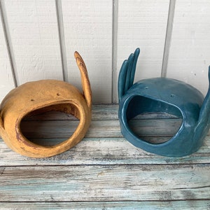 May include: Two ceramic planters shaped like hands with raised fingers. One planter is yellow and the other is blue.