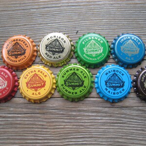 May include: Nine different Summit Brewing Company bottle caps, each featuring a different beer style. The caps are arranged in a circle on a wooden surface. The styles include Oktoberfest, Horizon Red Ale, Pilsener, India Pale Ale, Summer Ale, Extra Pale Ale, Maibock, Winter Ale, and Great Northern Porter.