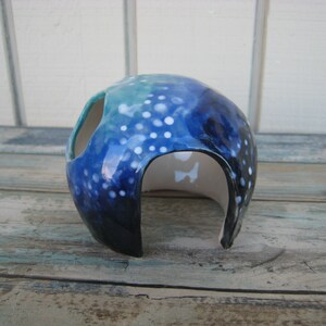 May include: A blue and white ceramic hide for small animals, with a round shape and a large opening. The hide is decorated with white dots and a blue and green gradient.