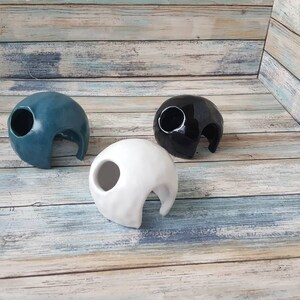 May include: Three ceramic reptile hides, one blue, one black, and one white. Each hide has a large opening for easy access.