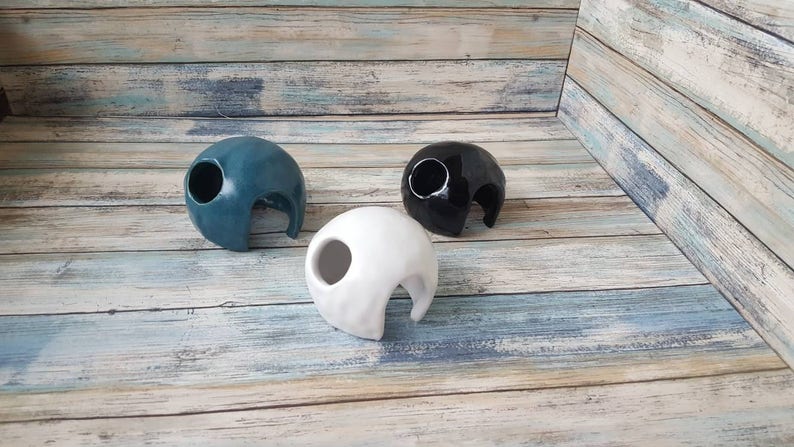 May include: Three ceramic reptile hides, one blue, one black, and one white. Each hide has a large opening for easy access.