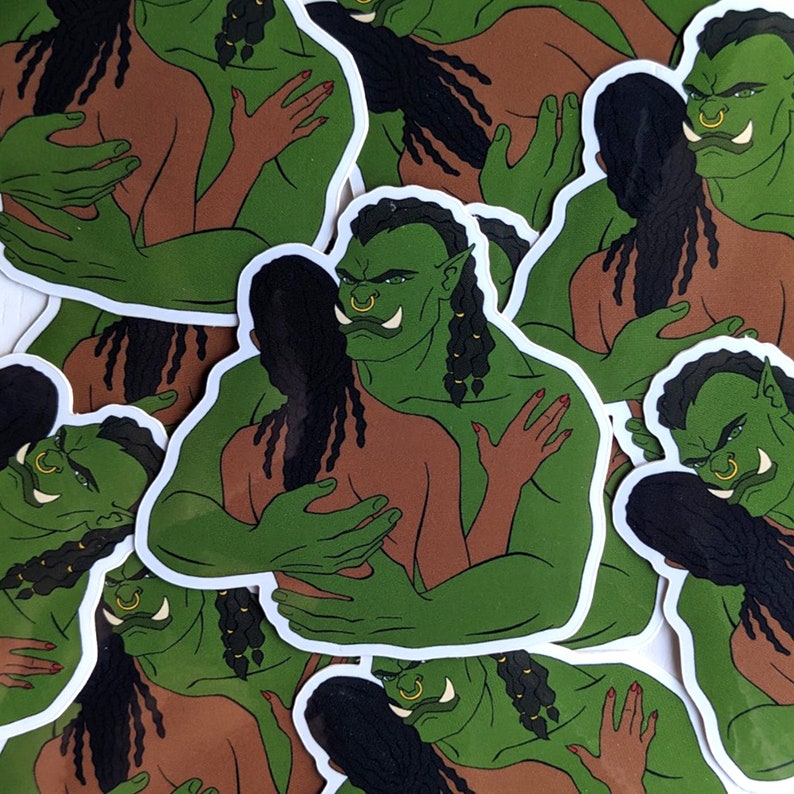 May include: A set of stickers featuring a green-skinned orc hugging a human with long black hair. The orc has a large nose ring and a fierce expression. The stickers are printed on white paper and have a glossy finish.