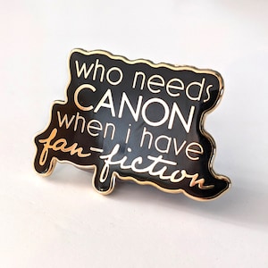 Könnte beinhalten: Schwarzer und goldener Emaille-Pin mit dem Text "Wer braucht Canon, wenn ich Fanfiction habe".
