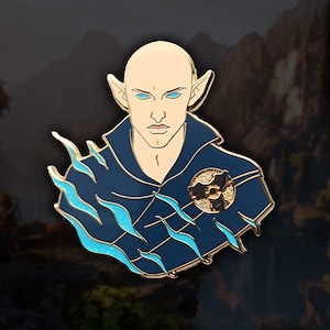 Puede incluir: Un pin de esmalte azul y dorado que representa a un elfo calvo con ojos azules y una marca roja en la frente. El elfo lleva una túnica azul oscuro con un símbolo dorado en el pecho. El pin tiene un diseño de llama azul y dorado en el lado izquierdo.