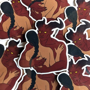 May include: A set of stickers featuring a red-skinned demon with horns embracing a person with long black hair. The demon has yellow eyes and a serious expression. The stickers are printed on white paper.