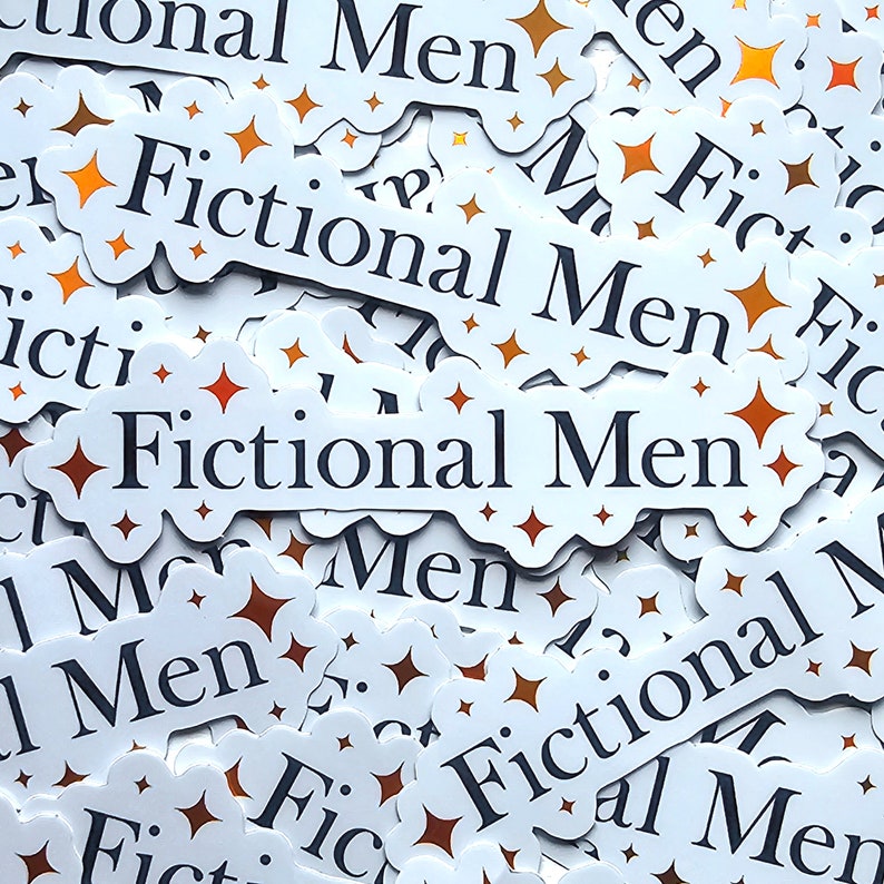 May include: A close-up of a pile of white stickers with the text "Fictional Men" printed in black. The stickers have a starburst design with orange and brown accents.