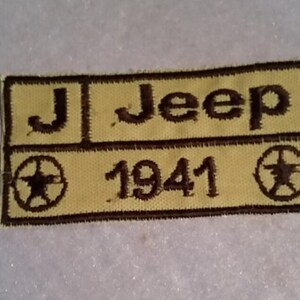 May include: A yellow and brown embroidered patch with the text "J. Jeep 1941" and a star design.