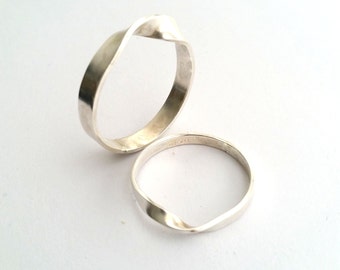 May include: Two silver rings with a twisted design. The rings are stacked on top of each other.