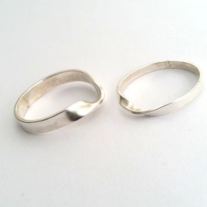 Puede incluir: Dos anillos de plata con un diseño retorcido. Los anillos son lisos y brillantes.