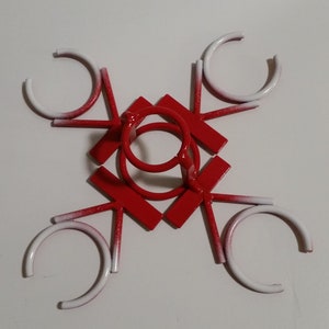 May include: Red metal wine glass holder with six white rings. The holder is shaped like a star with six points.