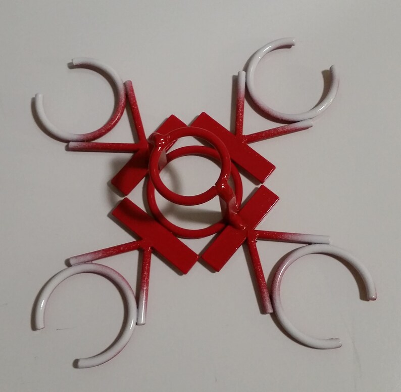 May include: Red metal wine glass holder with six white rings. The holder is shaped like a star with six points.
