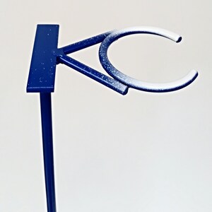 May include: A blue metal stand with a white-painted ring on top. The stand is designed to hold a variety of items, such as plants, cups, or other decorative objects.