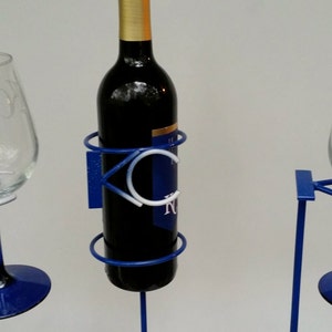 May include: A blue metal wine rack with two wine glasses. The rack has a circular design and the words "KC Royals" are visible on the front.
